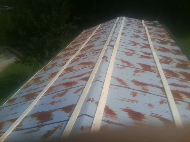 Rusted metal roof panels with new wood purlins before replacement — Storm Damage Roof Repair in Alden by Roofing Brothers