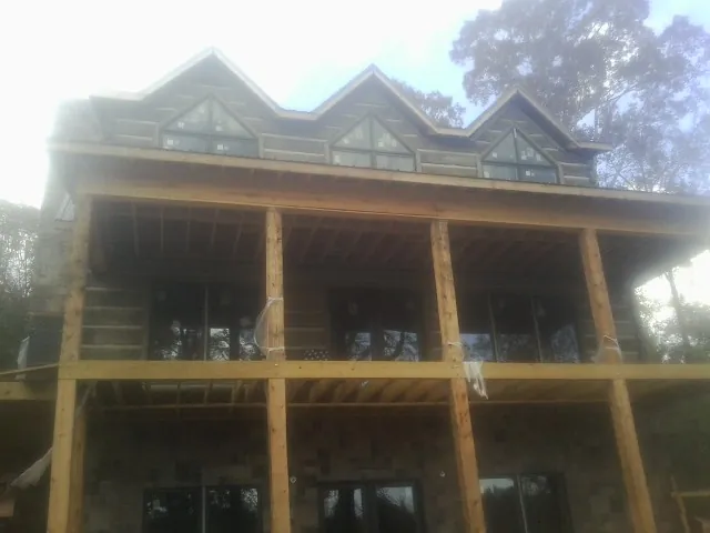 Dormers and porch framing on a large log home under construction — Roof Coating work by our crew in Alden