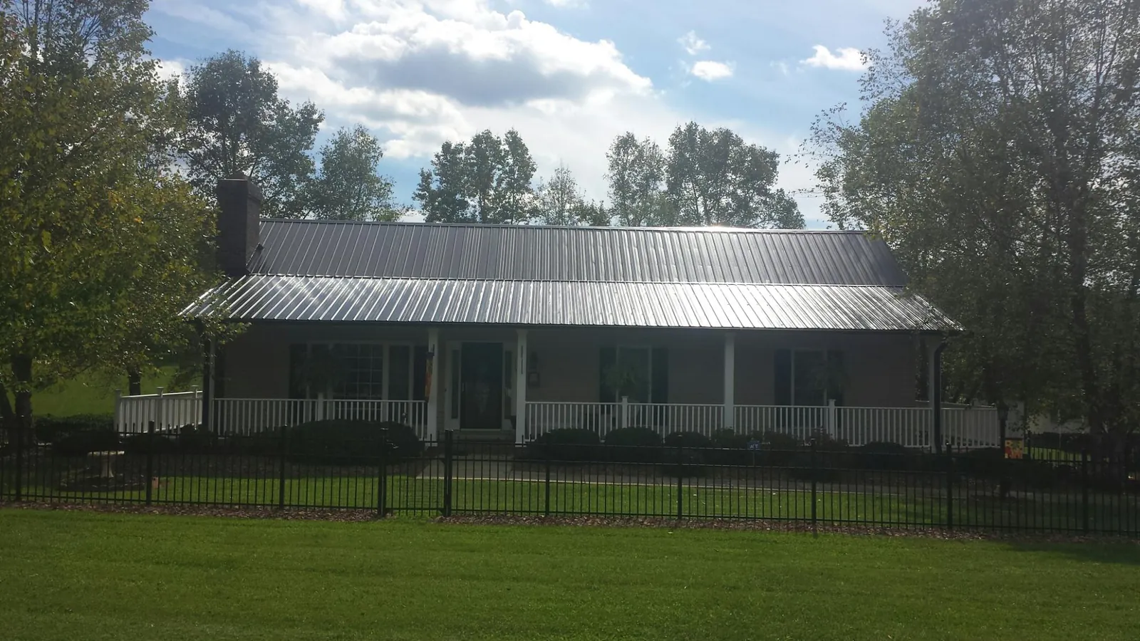 Gray metal roof on a brick ranch with a full width front porch — Gutter Guard Installation work by our crew in Alden